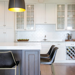 Large transitional kitchen inspiration - Large transitional medium tone wood floor and brown floor kitchen photo in Milwaukee with a farmhouse sink, quartz countertops, white backsplash, subway tile backsplash, stainless steel appliances, an island, white countertops, shaker cabinets and white cabinets