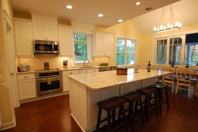 Inspiration for a large transitional u-shaped medium tone wood floor enclosed kitchen remodel in Columbus with an undermount sink, raised-panel cabinets, white cabinets, stainless steel appliances, an island, granite countertops, beige backsplash and ceramic backsplash