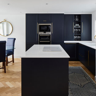 Inspiration for a medium sized classic l-shaped kitchen/diner in London with shaker cabinets, blue cabinets, quartz worktops, stainless steel appliances, an island, white worktops, a single-bowl sink and light hardwood flooring.