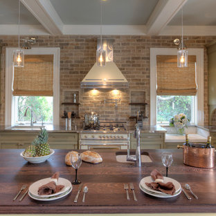 Photo of a large single-wall kitchen in Charleston with wood benchtops, stone tile splashback, white appliances, brown splashback, green cabinets, recessed-panel cabinets, an undermount sink and with island.