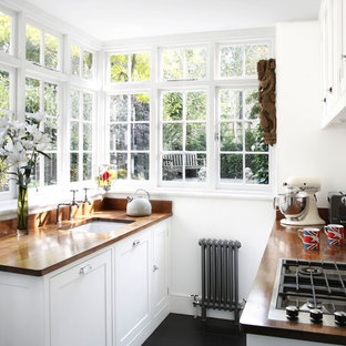 Immagine di una piccola cucina parallela tradizionale con lavello sottopiano, ante in stile shaker, ante bianche, top in legno e paraspruzzi bianco
