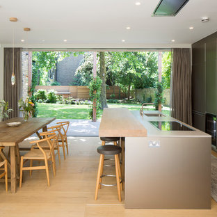 Photo of a modern kitchen/diner in London with a submerged sink, light hardwood flooring, an island, beige floors and white worktops.