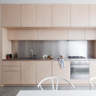 Design ideas for a modern single-wall kitchen/diner in London with an integrated sink, flat-panel cabinets, light wood cabinets, metallic splashback, metal splashback, stainless steel appliances, concrete flooring, no island, grey floors and grey worktops.