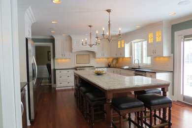 Large transitional l-shaped medium tone wood floor eat-in kitchen photo in New York with an undermount sink, beaded inset cabinets, white cabinets, granite countertops, white backsplash, ceramic backsplash, stainless steel appliances and an island