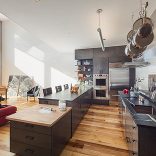 Example of an urban medium tone wood floor open concept kitchen design in Philadelphia with an undermount sink, flat-panel cabinets, metallic backsplash, metal backsplash, stainless steel appliances, two islands and multicolored countertops