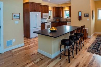 Inspiration for a large craftsman u-shaped light wood floor and brown floor open concept kitchen remodel in DC Metro with an undermount sink, shaker cabinets, medium tone wood cabinets, solid surface countertops, beige backsplash, ceramic backsplash, white appliances and an island
