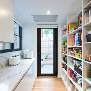 Photo of a contemporary kitchen in Melbourne with open cabinets, white splashback, medium hardwood floors, brown floor and white benchtop.