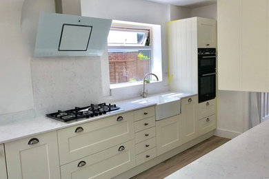 Photo of a medium sized classic galley kitchen/diner in Buckinghamshire with a belfast sink, shaker cabinets, quartz worktops, integrated appliances, vinyl flooring and no island.