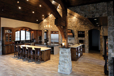 Example of a huge u-shaped open concept kitchen design in Salt Lake City with a farmhouse sink, recessed-panel cabinets, dark wood cabinets, granite countertops, stainless steel appliances and two islands