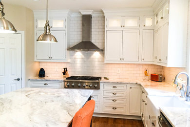 Example of a large transitional u-shaped light wood floor kitchen design in Cincinnati with a farmhouse sink, shaker cabinets, white cabinets, quartzite countertops, white backsplash, porcelain backsplash, stainless steel appliances and an island