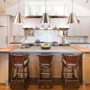 This is an example of a large country separate kitchen in New York with an undermount sink, white cabinets, metallic splashback, metal splashback, panelled appliances, with island, shaker cabinets, concrete benchtops and orange floor.