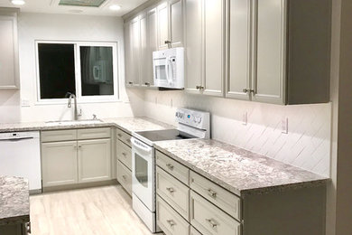 This is an example of a medium sized contemporary l-shaped kitchen/diner in Phoenix with a submerged sink, flat-panel cabinets, grey cabinets, engineered stone countertops, white splashback, metro tiled splashback, white appliances, porcelain flooring, no island and grey floors.