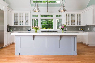 Mid-sized transitional u-shaped medium tone wood floor and brown floor eat-in kitchen photo in Providence with an undermount sink, recessed-panel cabinets, white cabinets, quartzite countertops, green backsplash, subway tile backsplash, stainless steel appliances, an island and white countertops