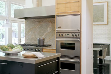 Contemporary u-shaped open plan kitchen in St Louis with flat-panel cabinets, black cabinets, stainless steel worktops, grey splashback, stone slab splashback, stainless steel appliances, a single-bowl sink, painted wood flooring, an island and black floors.