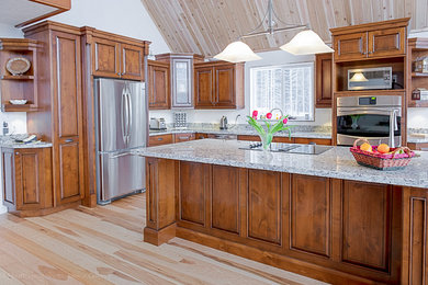 Esempio di una cucina classica di medie dimensioni con lavello sottopiano, ante con bugna sagomata, ante in legno bruno, top in granito, parquet chiaro e pavimento marrone