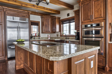Design ideas for a medium sized classic l-shaped kitchen in Vancouver with a belfast sink, raised-panel cabinets, dark wood cabinets, granite worktops, stainless steel appliances, dark hardwood flooring, an island and brown floors.