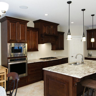 Design ideas for a mid-sized traditional eat-in kitchen with a double-bowl sink, raised-panel cabinets, dark wood cabinets, limestone benchtops, stainless steel appliances, terra-cotta floors and with island.