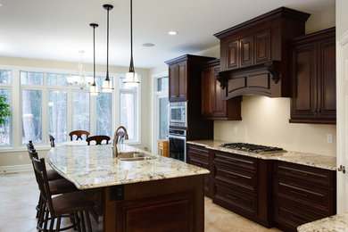 Example of a mid-sized classic terra-cotta tile eat-in kitchen design with a double-bowl sink, raised-panel cabinets, dark wood cabinets, limestone countertops, stainless steel appliances and an island