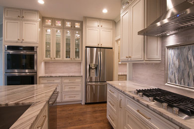 Inspiration for a large timeless l-shaped dark wood floor and brown floor open concept kitchen remodel in Raleigh with an undermount sink, recessed-panel cabinets, white cabinets, granite countertops, beige backsplash, porcelain backsplash, stainless steel appliances, an island and multicolored countertops