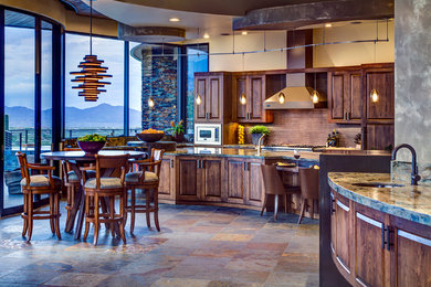 Inspiration for a huge southwestern galley eat-in kitchen remodel in Phoenix with raised-panel cabinets, dark wood cabinets, granite countertops, brown backsplash, mosaic tile backsplash, paneled appliances and an island