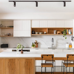 Photo of a transitional u-shaped open plan kitchen in Wollongong with an undermount sink, raised-panel cabinets, white cabinets, grey splashback, black appliances, concrete floors, with island and grey floor.