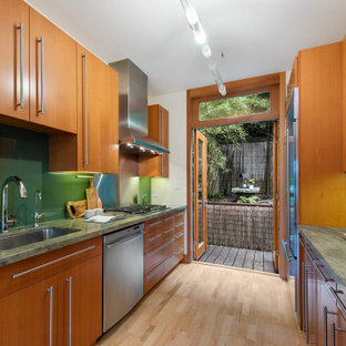 This is an example of a small asian galley separate kitchen in San Francisco with a single-bowl sink, flat-panel cabinets, light wood cabinets, marble benchtops, green splashback, glass sheet splashback, stainless steel appliances, light hardwood floors, no island, beige floor and green benchtop.