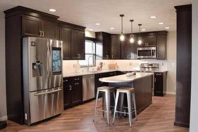 Example of a l-shaped kitchen design in Other with a single-bowl sink, shaker cabinets, dark wood cabinets, granite countertops, white backsplash, stainless steel appliances and an island