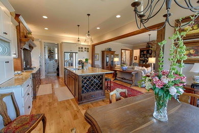 Example of a large transitional l-shaped medium tone wood floor and brown floor eat-in kitchen design in Birmingham with an undermount sink, stainless steel appliances, shaker cabinets, white cabinets, granite countertops and an island