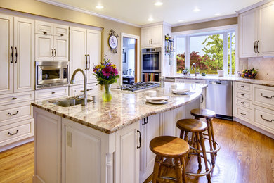 Kitchen - traditional kitchen idea in Seattle with raised-panel cabinets, white cabinets, beige backsplash and stainless steel appliances