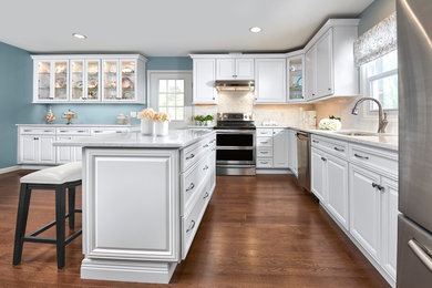 Kitchen - large traditional l-shaped medium tone wood floor and brown floor kitchen idea in Indianapolis with an undermount sink, raised-panel cabinets, white cabinets, white backsplash, subway tile backsplash, stainless steel appliances, an island and white countertops