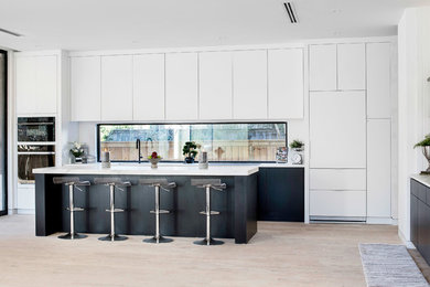Ejemplo de cocinas en L contemporánea de tamaño medio abierta con armarios con paneles lisos, puertas de armario blancas, encimera de cuarcita, una isla y encimeras blancas