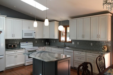 Example of a mid-sized transitional l-shaped medium tone wood floor and brown floor eat-in kitchen design in Cincinnati with an undermount sink, shaker cabinets, white cabinets, quartzite countertops, gray backsplash, glass tile backsplash, white appliances, an island and gray countertops