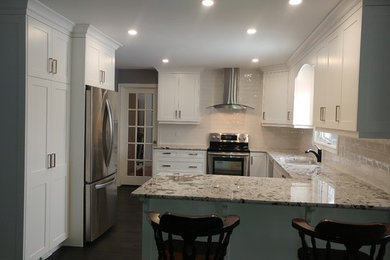 Inspiration for a mid-sized transitional u-shaped dark wood floor and brown floor eat-in kitchen remodel in Toronto with a double-bowl sink, shaker cabinets, white cabinets, granite countertops, white backsplash, subway tile backsplash, stainless steel appliances and a peninsula