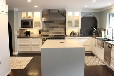Large minimalist l-shaped laminate floor eat-in kitchen photo in Los Angeles with a farmhouse sink, shaker cabinets, white cabinets, quartz countertops, brown backsplash, porcelain backsplash, stainless steel appliances and an island