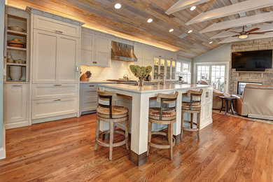 Example of a large transitional single-wall medium tone wood floor open concept kitchen design in New York with white cabinets, quartz countertops, paneled appliances, an island, recessed-panel cabinets, white backsplash, an undermount sink and glass tile backsplash