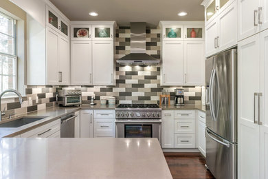 Mid-sized trendy u-shaped medium tone wood floor and brown floor open concept kitchen photo in Austin with an undermount sink, white cabinets, quartzite countertops, multicolored backsplash, porcelain backsplash, stainless steel appliances, a peninsula, gray countertops and shaker cabinets