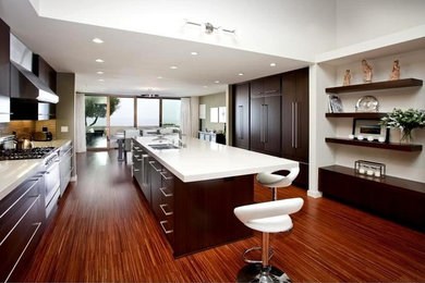 Photo of a large contemporary u-shaped open plan kitchen in Los Angeles with a submerged sink, flat-panel cabinets, dark wood cabinets, quartz worktops, stainless steel appliances, medium hardwood flooring and an island.