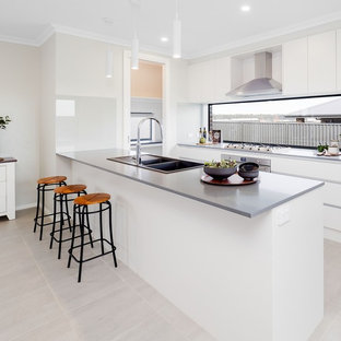 Mid-sized contemporary galley open plan kitchen in Sydney with a double-bowl sink, flat-panel cabinets, white cabinets, quartz benchtops, stainless steel appliances, ceramic floors, grey benchtop, window splashback, a peninsula and grey floor.