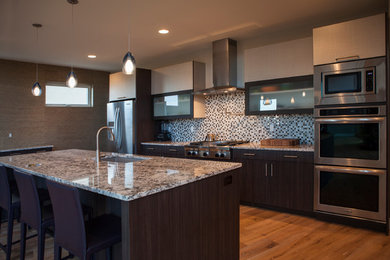 Example of a mid-sized trendy galley light wood floor and brown floor open concept kitchen design in Denver with an undermount sink, flat-panel cabinets, dark wood cabinets, granite countertops, multicolored backsplash, glass tile backsplash, stainless steel appliances and an island