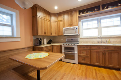 L-shaped kitchen photo in Chicago with shaker cabinets, light wood cabinets, white appliances and no island