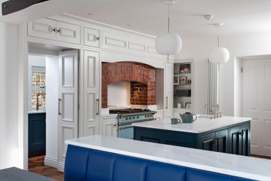 Idéer för ett stort medelhavsstil vit l-kök, med en undermonterad diskho, luckor med infälld panel, vita skåp, färgglada vitvaror, en köksö och brunt golv