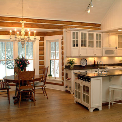 Example of a mountain style l-shaped eat-in kitchen design in Grand Rapids with glass-front cabinets, white cabinets, white backsplash and paneled appliances