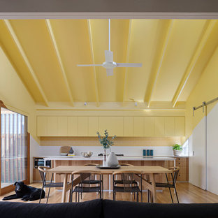 Photo of a contemporary galley open plan kitchen in Geelong with flat-panel cabinets, yellow cabinets, yellow splashback, subway tile splashback, medium hardwood floors, with island and brown floor.
