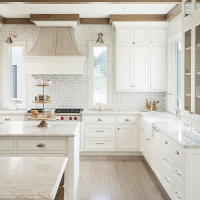 Kitchen - transitional l-shaped light wood floor and beige floor kitchen idea in Denver with a farmhouse sink, recessed-panel cabinets, white cabinets, white backsplash, mosaic tile backsplash, two islands and beige countertops