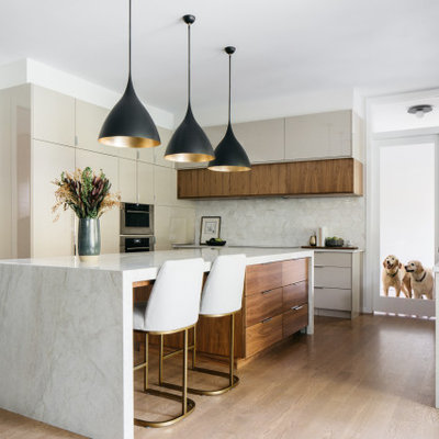 Kitchen - contemporary u-shaped medium tone wood floor and brown floor kitchen idea in Chicago with flat-panel cabinets, gray cabinets, stainless steel appliances, an island and white countertops