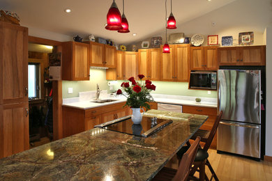 Cette photo montre une cuisine ouverte chic en L et bois brun avec un évier encastré, un placard à porte shaker, plan de travail en marbre, une crédence verte et un électroménager en acier inoxydable.