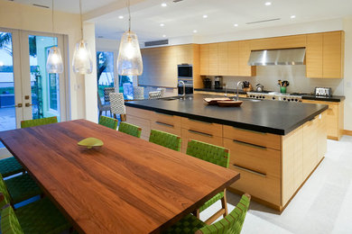 Foto de cocina minimalista con armarios con paneles lisos, puertas de armario de madera clara y electrodomésticos de acero inoxidable