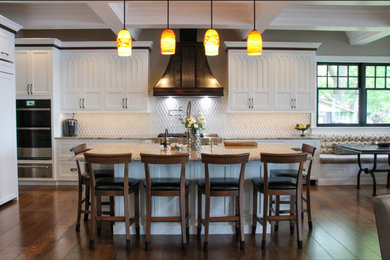 Inspiration for a large transitional l-shaped medium tone wood floor, brown floor and coffered ceiling open concept kitchen remodel in Other with a farmhouse sink, recessed-panel cabinets, white cabinets, granite countertops, white backsplash, stainless steel appliances, an island and beige countertops