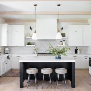 Esempio di una cucina ad U stile marinaro con lavello stile country, ante in stile shaker, ante bianche, paraspruzzi bianco, elettrodomestici in acciaio inossidabile, parquet chiaro, isola, pavimento beige, top bianco e travi a vista
