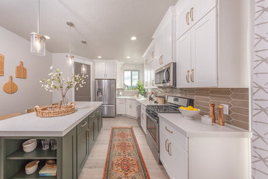 Eat-in kitchen - mid-sized l-shaped laminate floor and beige floor eat-in kitchen idea in Salt Lake City with an undermount sink, shaker cabinets, white cabinets, quartzite countertops, brown backsplash, glass tile backsplash, stainless steel appliances, an island and white countertops